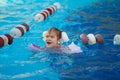 a funny little girl swims in inflatable armbands in a pool near the buoys. Royalty Free Stock Photo