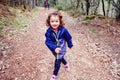 Funny little girl walks through a forest taking a family walk in autumn