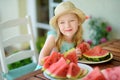 Funny little girl wearing straw hat biting a slice of watermelon outdoors on warm and sunny summer day. Royalty Free Stock Photo