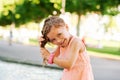 Funny little girl wetting hair in fountain hot summer day