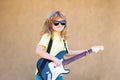 Funny little hipster musician child playing guitar. Funny rock child with guitar. Little boy in sunglasses. Kids music Royalty Free Stock Photo