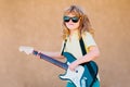 Funny little hipster musician child playing guitar. Funny rock child with guitar. Little boy in sunglasses. Kids music