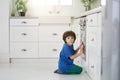 Little foodie. Funny little hispanic boy looking surprised at camera while watching cake baking in the oven, crouching Royalty Free Stock Photo