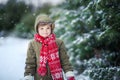 Funny little kid boy in colorful clothes playing outdoors during snowfall. Active leisure with children in winter on