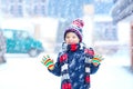 Funny little kid boy in colorful clothes playing outdoors during strong snowfall Royalty Free Stock Photo