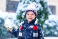 Funny little kid boy in colorful clothes playing outdoors during strong snowfall Royalty Free Stock Photo