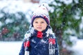 Funny little kid boy in colorful clothes playing outdoors during strong snowfall Royalty Free Stock Photo