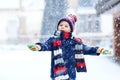 Funny little kid boy in colorful clothes playing outdoors during strong snowfall Royalty Free Stock Photo