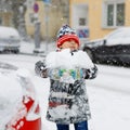 Funny little kid boy in colorful clothes playing outdoors during strong snowfall. Active leisure with children in winter Royalty Free Stock Photo