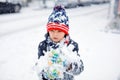 Funny little kid boy in colorful clothes playing outdoors during strong snowfall. Active leisure with children in winter Royalty Free Stock Photo