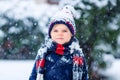 Funny little kid boy in colorful clothes playing outdoors during strong snowfall Royalty Free Stock Photo