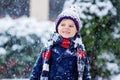 Funny little kid boy in colorful clothes playing outdoors during strong snowfall Royalty Free Stock Photo