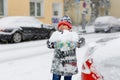 Funny little kid boy in colorful clothes playing outdoors during strong snowfall. Active leisure with children in winter Royalty Free Stock Photo