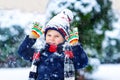 Funny little kid boy in colorful clothes playing outdoors during strong snowfall Royalty Free Stock Photo