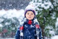 Funny little kid boy in colorful clothes playing outdoors during strong snowfall Royalty Free Stock Photo