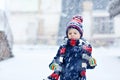 Funny little kid boy in colorful clothes playing outdoors during strong snowfall Royalty Free Stock Photo