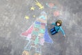 Funny little kid boy flying in universe by a space shuttle picture painting with colorful chalks. Creative leisure for