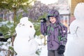 Funny little kid boy making a snowman and eating carrot, playing having fun with snow, outdoors on cold day. Active leisure childr