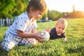 Funny little kids playing with ball on green grass on nature at summer day. Two brothers outdoors. Preschool boy and baby boy. Chi Royalty Free Stock Photo