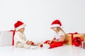 Funny little kids in Santa hat sitting between gift boxes and playing with christmas balls. Isolated on white background. New year Royalty Free Stock Photo