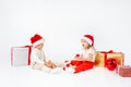 Funny little kids in Santa hat sitting between gift boxes and playing with christmas balls. Isolated on white background. New year Royalty Free Stock Photo