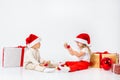 Funny little kids in Santa hat sitting between gift boxes and playing with christmas balls. Isolated on white background. New year Royalty Free Stock Photo