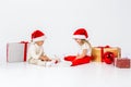 Funny little kids in Santa hat sitting between gift boxes and playing with christmas balls. Isolated on white background. New year Royalty Free Stock Photo