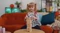 Funny little one teen kid girl play wooden tower blocks bricks game at home in modern living room Royalty Free Stock Photo