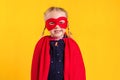 Funny little power superhero child girl in a red raincoat and a mask. Superhero concept.