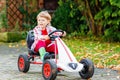 Funny little preschhool boy having fun and driving pedal race car in home's garden. Active games for children in Royalty Free Stock Photo