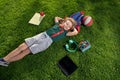 Funny little school child with digital gadgets and backpacks sitting at the grass park outdoors. Top view of little boy Royalty Free Stock Photo