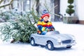 Funny little smiling kid boy driving toy car with Christmas tree. Royalty Free Stock Photo