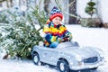 Funny little smiling kid boy driving toy car with Christmas tree. Royalty Free Stock Photo