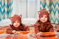 Funny little twins lie on blanket at home in blouses with animal ears Royalty Free Stock Photo