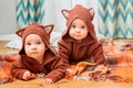 Funny little twins lie on blanket at home in blouses with animal ears Royalty Free Stock Photo