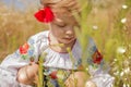 Funny little Ukrainian Caucasian girl in an embroidered shirt playing in a meadow where wild flowers Royalty Free Stock Photo