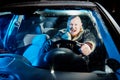Funny male driver in a leather jacket in the car in the dark. Night photo shoot