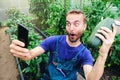 Funny male farmer making selfie on smartphone with fresh harvested vegetables in his greenhouse