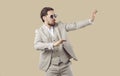 Funny young man in classic suit and cool sunglasses dancing on beige studio background