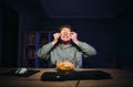 Funny male gamer puts chips on his eyes and smiles while streaming a game on the computer at night with a smile on his face. Guy Royalty Free Stock Photo