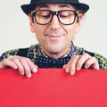 Funny male nerd looking down on empty red poster. Happy man in glasses holding sheet of paper for your text. People and Royalty Free Stock Photo