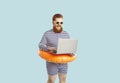 Funny man in anticipation of summer vacation using laptop booking tour on light blue background.