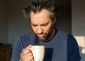 Funny man after awakening looking at his a big cup of coffee or tea. Royalty Free Stock Photo