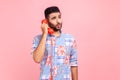 Funny man with beard wearing blue casual style shirt holding phone handset, having conversation, unbelievable news, standing with Royalty Free Stock Photo