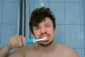 Funny man is brushing teeth usin electric toothbrush and making cheerful faces. Royalty Free Stock Photo