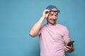 Funny man raised glasses to forehead and reads a message on a smartphone, with a strange expression on face. Copy space Royalty Free Stock Photo