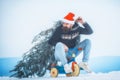 Funny man carrying xmas tree on white snow. Crazy cyclist in santa hat and sporty wear riding on bicycle on snowy Royalty Free Stock Photo