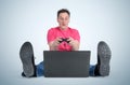 Funny man gamer sitting on the floor playing on laptop Royalty Free Stock Photo