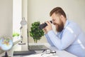 Funny man looking searching binoculars a laptop on the table working at home office. Royalty Free Stock Photo