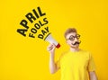 Funny man with megaphone on color background. April Fools' Day prank Royalty Free Stock Photo